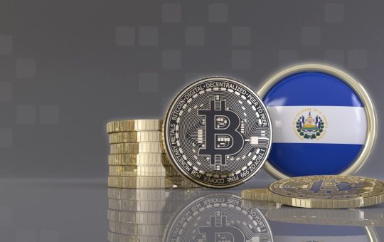 An artistic rendering of bitcoins tokens in front of a badge emblazoned with the flag of El Salvador.